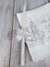 Kit de batizado com toalha branca bordada e vela decorada com laço branco.