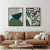 Dois quadros decorativos com design botânico em uma sala com sofá de couro marrom e mesa de centro.