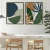 Dois quadros decorativos com design botânico em cores verdes, azuis e terracota, expostos em uma parede de um ambiente moderno.