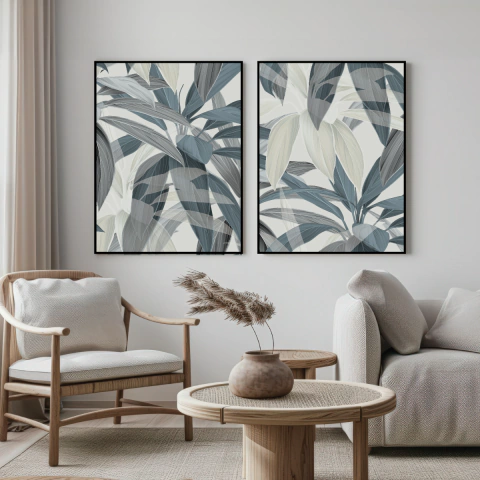 Dois quadros decorativos com folhas em tons de azul e verde, emoldurados, pendurados em uma parede clara, ao lado de móveis modernos como uma poltrona de madeira e uma mesa redonda.