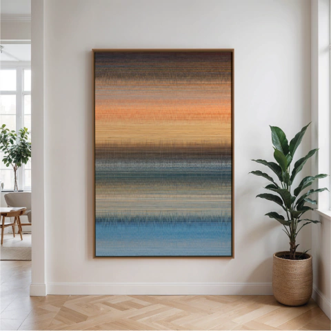 Quadro decorativo em canvas com padrão abstrato em degrade de cores que vão do azul ao laranja, pendurado em parede branca ao lado de planta em vaso de palha