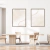 Dois quadros decorativos em estilo minimalista com tons suaves de bege e linhas delicadas, pendurados em uma parede branca acima de uma mesa de madeira clara e cadeiras.