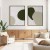 Quadro decorativo em duas peças com formas abstratas em tons de verde e bege, emoldurados e expostos em uma sala de estar moderna.