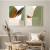 Dois quadros decorativos com formas abstratas em tons de verde e marrom, pendurados em uma parede clara, com uma cadeira de madeira e vasos decorativos ao fundo.