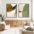 Dois quadros decorativos com pinturas abstratas em tons de verde e marrom, emoldurados em preto, dispostos em uma parede branca.