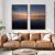 Quadro decorativo em duas peças retratando um pôr do sol no horizonte, em um ambiente moderno com sofá de couro.