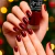 Unhas com esmalte vermelho escuro da Anita, coleção especial de Natal, segurando o frasco do esmalte