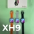 A imagem mostra quatro smartwatches com pulseiras coloridas (laranja, cinza, lavanda e preta) dispostos em uma fileira. Cada relógio tem uma tela retangular e um design moderno, destacando-se pelas cores vibrantes das pulseiras. Esta imagem pode ser relev