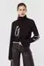 Suéter negro de mujer con cuello alto y detalles en blanco, combinado con pantalones de cuero.