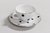 taza de te con plato de porcelana blanca con lunares negros y borde de oro