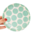 Plato de postre con diseño de círculos en colores mint y blanco, sostenido por una mano.