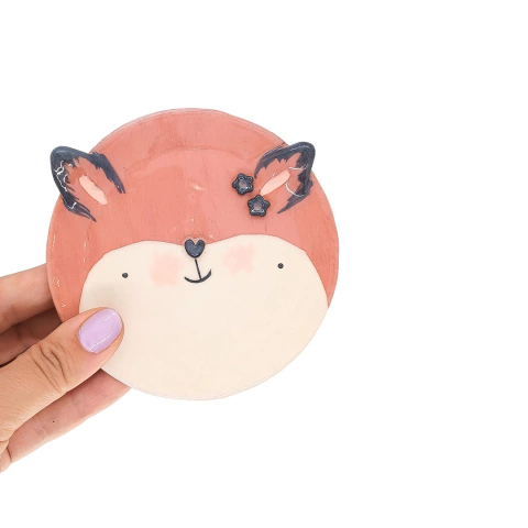 Platito apoya cucharas en forma de zorrito, con detalles artísticos en colores suaves.