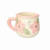Taza decorada con flores rosas y hojas verdes, ideal para el hogar.