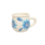 Taza de cerámica blanca decorada con flores azules y hojas verdes.