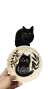 Plato de cerámica con diseño de gatito negro, sostenido por una mano. Fondo blanco.