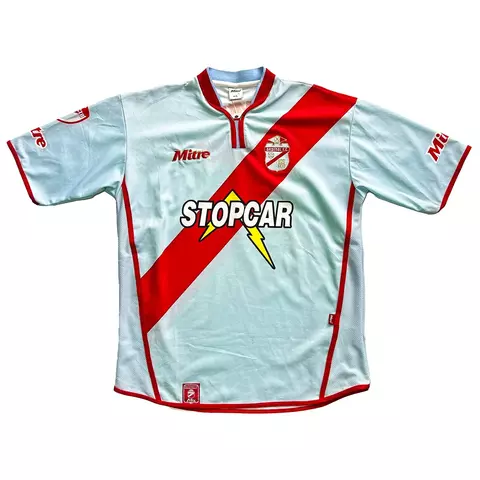 Camisa de futebol Mitre do Arsenal de Sarandi 2004/2005, modelo home, com faixa diagonal vermelha sobre fundo azul claro e logo do patrocinador Stopcar no centro