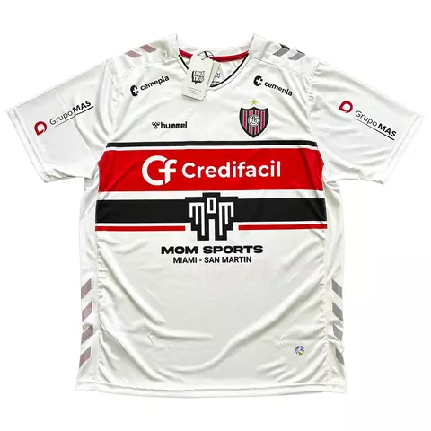 Camisa de futebol Hummel Chacarita 2023 modelo Away na cor branca com listras horizontais vermelha e preta, com logos dos patrocinadores e escudo do clube no peito