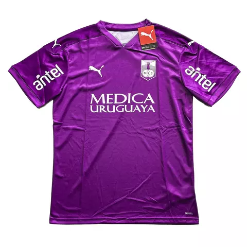 Camisa de futebol Puma Defensor 2020/2021 na cor roxa com logos da Puma, patrocinadores Médica Uruguaya e Antel, e escudo do time Defensor Sporting Club