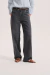 Jean Barrel de mujer en denim negro, tiro alto y silueta amplia, combinado con camisa celeste y sandalias marrones.