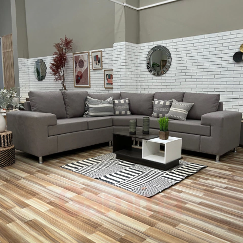 Esquinero Living Libra de tres cuerpos en color gris, con cojines decorativos, ubicado en un ambiente moderno con paredes blancas y decoración minimalista. Conseguilo en Gamma Hogar.