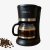 Cafetera negra Kanji de 12 tazas con jarra de vidrio y café recién hecho, junto a granos de café. Conseguila en Gamma Hogar.