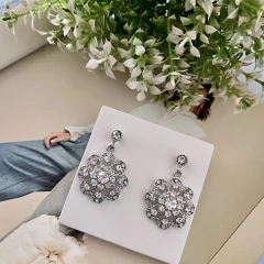 Brinco banhado em formato de flor com pedras brilhantes.