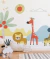 Papel de parede infantil colorido com tema safari mostrando desenhos de leão, girafa, zebra, sol e árvores em quarto de menino