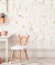 Papel de parede infantil com estampa floral delicada em tons pastéis com borboletas, em quarto decorado com cadeira de madeira e mesa branca