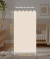 Meia parede com papel de parede bege fendi ondulado, criando uma base neutra e delicada para o quarto infantil.