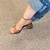 Sandália de salto bloco médio bico folha bronze em um pé feminino com calça jeans.