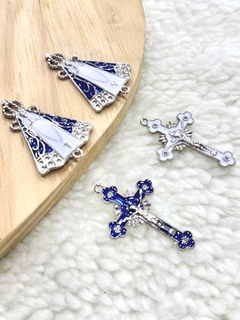 Quatro peças de entremeio em níquel representando Nossa Senhora Aparecida e cruzes, com detalhes em azul e branco.