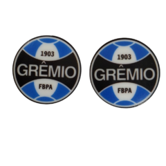 Aplique acrílico com o logo do Grêmio, medindo 3 cm, em cores azul, preto e branco.
