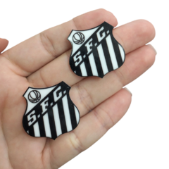 Aplique Santos Acrílico de 3 cm em mão, com as cores preta e branca, representando o escudo do time de futebol Santos.