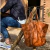 tote bag de cuero grande marrón colgada de una silla de madera