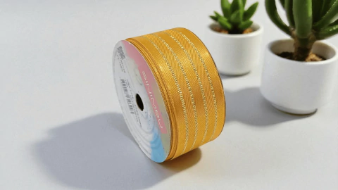 Rolo de fita decorativa Sinimbu na cor ouro com 38mm de largura e 10 metros de comprimento, com detalhes em linhas douradas metálicas