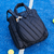 Bolso Paletero Neo Bag Bomber Negro sobre una cancha azul con una pala de pádel asomando.
