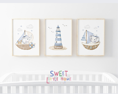 Três quadros infantis decorativos com ilustrações de elefantes marinheiros e um farol em um ambiente de quarto de bebê.