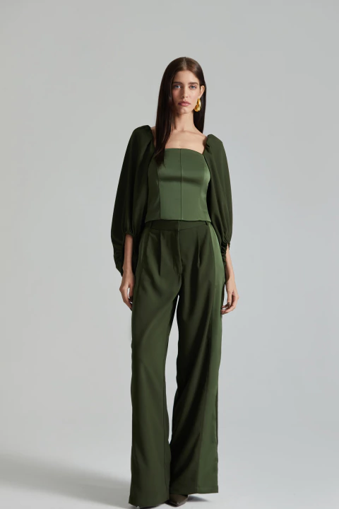 Mulher vestindo calça verde wide com caimento fluido e blusa verde com mangas bufantes