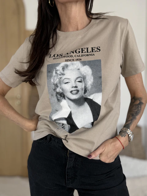 Remera de algodón beige con estampa de Marilyn Monroe y texto "Los Angeles" en el frente, modelo de mujer posando con pantalón negro.