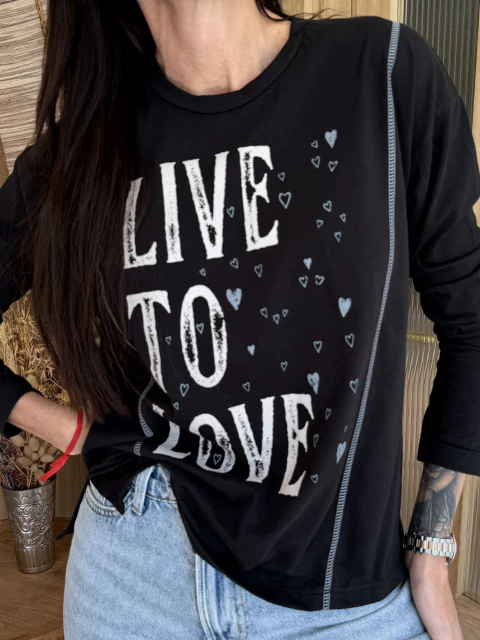 Remera negra de manga larga LAST LOVE con estampa "LIVE TO LOVE", detalles de costuras a contratono y jeans claros, modelo femenina.