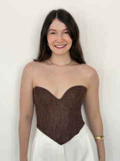 Mulher sorridente usando corset marrom de renda com estampa floral e calça branca