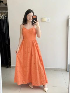 Mulher sorrindo usando vestido longo laranja em laise com alças finas, tirando selfie em espelho