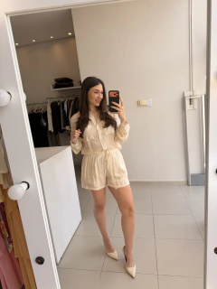 Mulher tirando selfie em espelho vestindo conjunto feminino leve cor creme com camisa de manga longa e short com cós de lastex