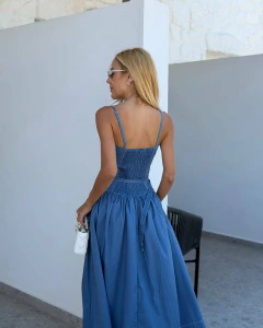 Mulher vista de costas usando vestido azul estilo Georgia com alças finas e lastex nas costas, segurando bolsa branca pequena