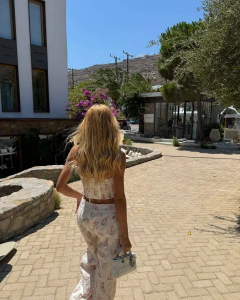 Mulher vista de costas usando conjunto Yasmin estampado com top corset e calça larga, caminhando ao ar livre em dia ensolarado