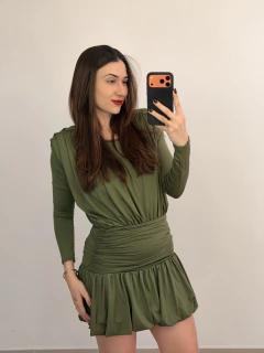 Mulher tirando selfie com smartphone, vestindo conjunto verde de malha com saia drapeada e blusa de manga longa