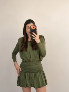 Mulher tirando selfie com celular, vestindo conjunto verde de malha com saia drapeada e blusa estruturada